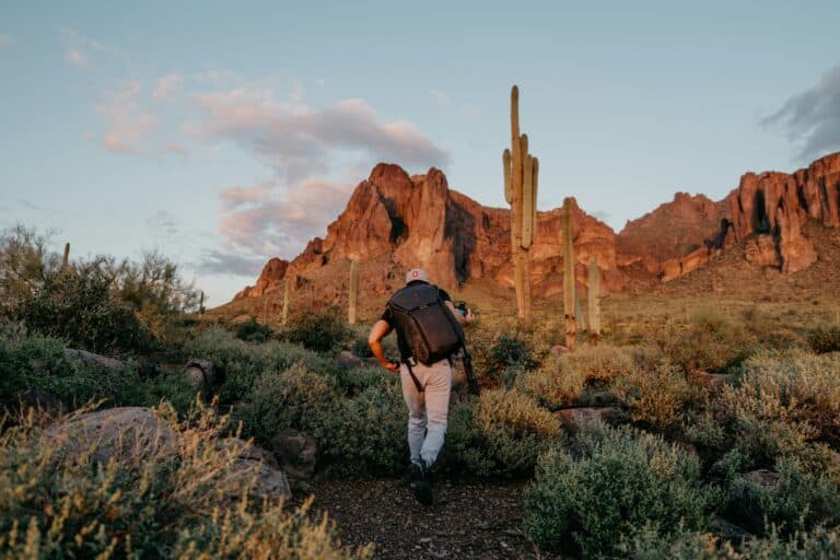 Solitary hiker on a red rock desert trail at golden hour, Arizona