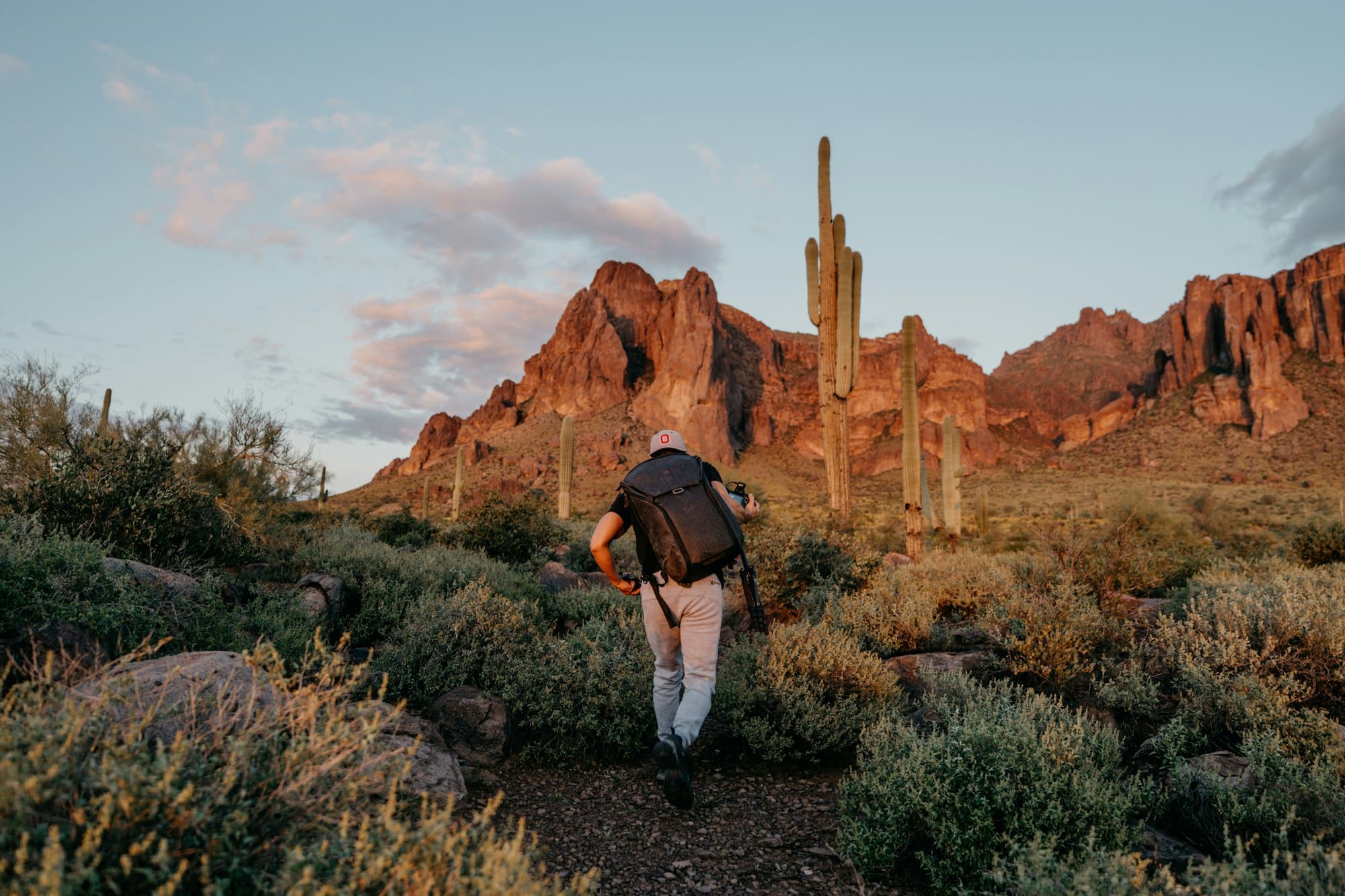 Solitary hiker on a red rock desert trail at golden hour, Arizona