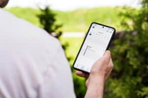 Person holding a smartphone checking a calendar outdoors