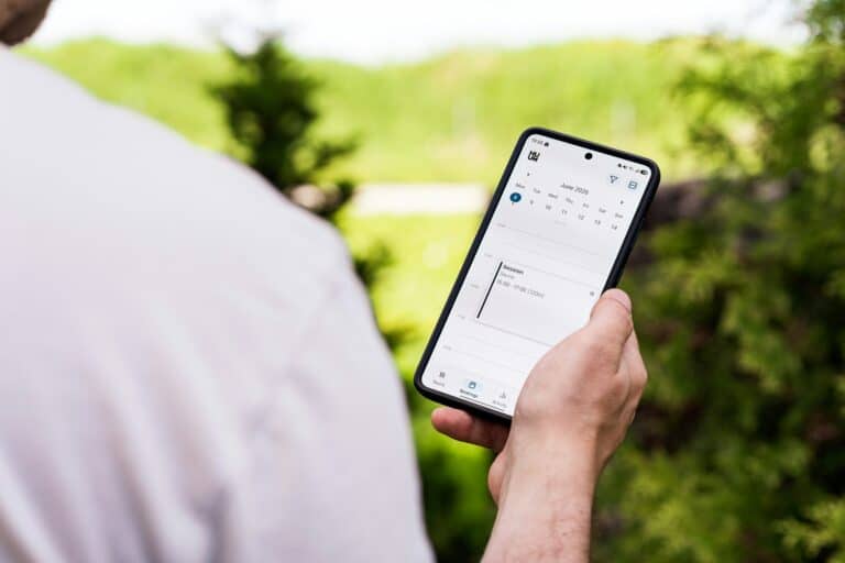 Person holding a smartphone checking a calendar outdoors