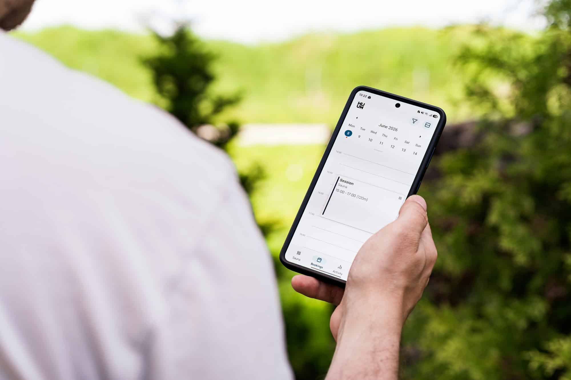 Person holding a smartphone checking a calendar outdoors