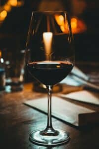 Glass of red wine on a dark wood bar under warm light