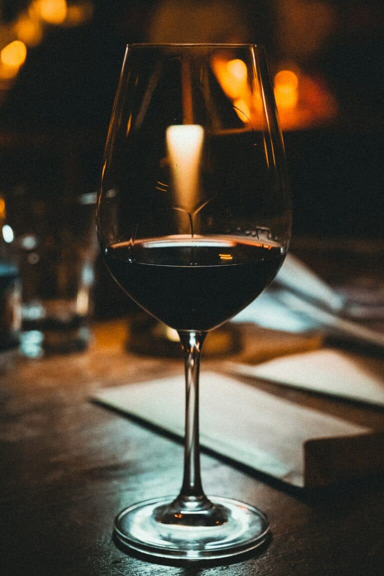 Glass of red wine on a dark wood bar under warm light